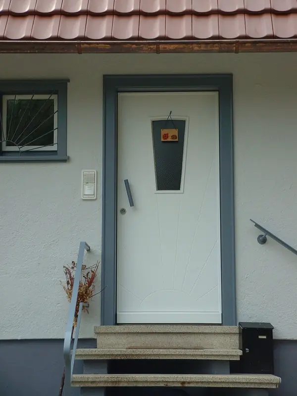 Weiße Haustür aus Holz mit Sonnenmotiv