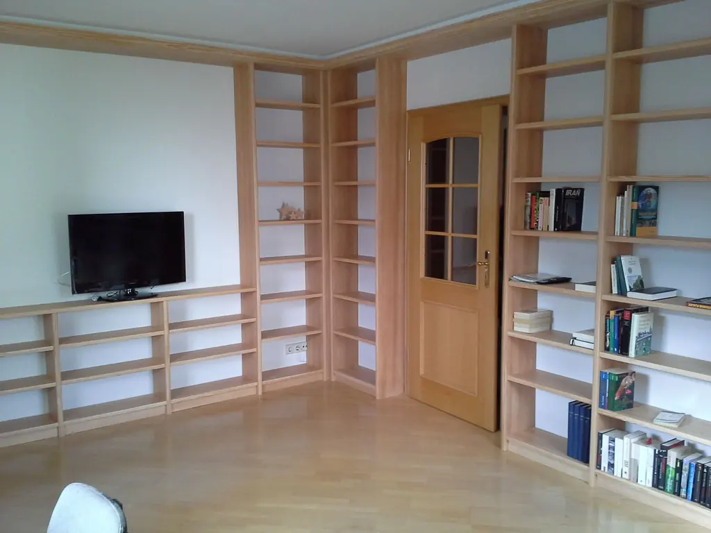 Regalwand und Lowboard aus Esche über Eck im Wohnzimmer, mit eingebundener Zimmertür