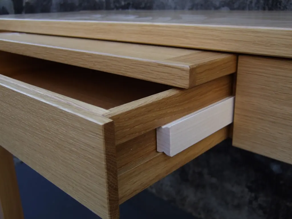 Geöffnete Schublade mit Holzführung an einem Schreibtisch aus Eiche
